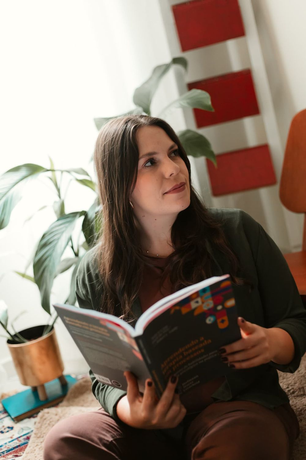 Camila Andrade lendo um livro de psicologia, sentada junto a plantas